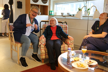 Dietisten Lena sitter i en fåtölj, bredvid henne sitter en äldre dam och en sjuksköterska. Alla skrattar och är glada.