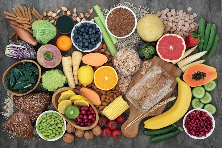 Bild på fiberrika livsmedel frukt, bönor och fullkornsbröd.