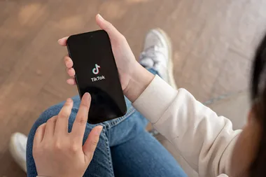 En hand håller en mobil som visar symbolen för TikTok.