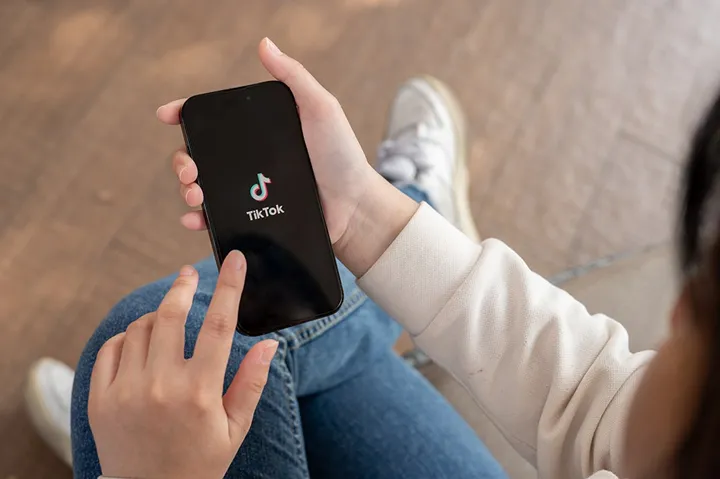 En hand håller en mobil som visar symbolen för TikTok.