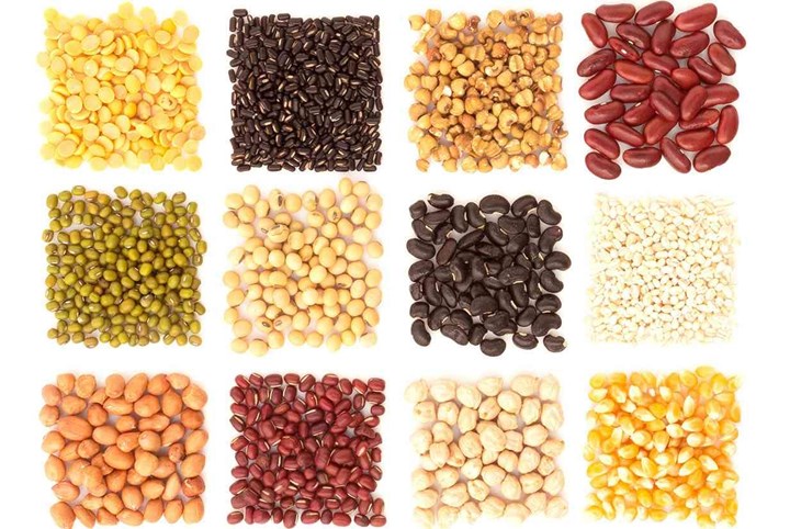 Assortment of beans and lentils in wooden spoon with wood box macadamia isolated on white . mung bean groundnut soybean red kidney bean black bean red bean and brown pinto beans .
