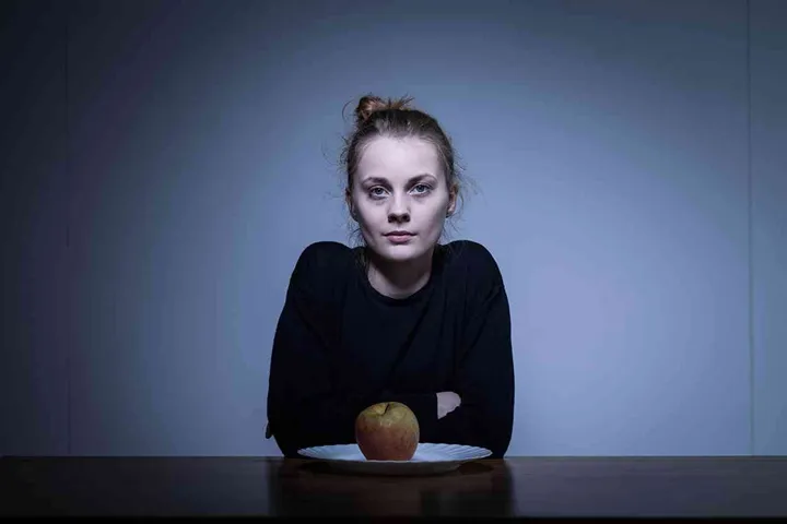 Anorectic young girl eating apple for dinner